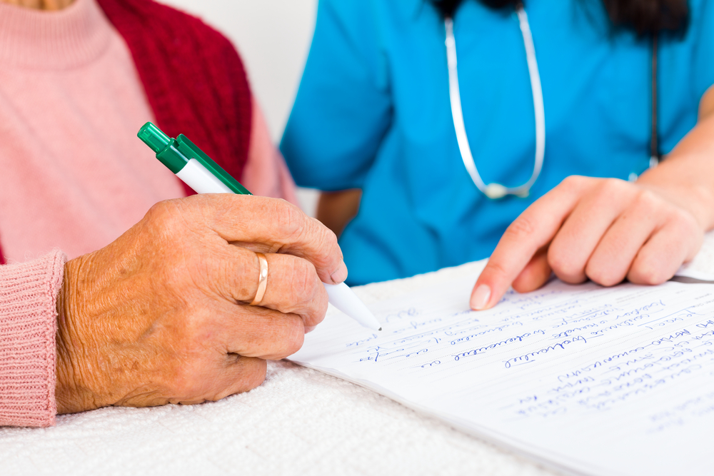 Senior woman and nurse reviewing legal contract